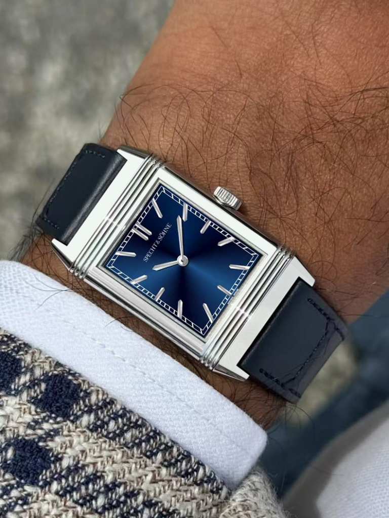 Specht & Söhne Overturn reversible watch worn on wrist, featuring a blue sunburst dial, rectangular stainless steel case, and black leather strap.