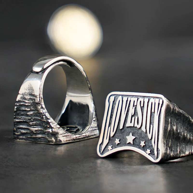 Front and side view of Lovesick engraved 925 sterling silver ring for men on dark background