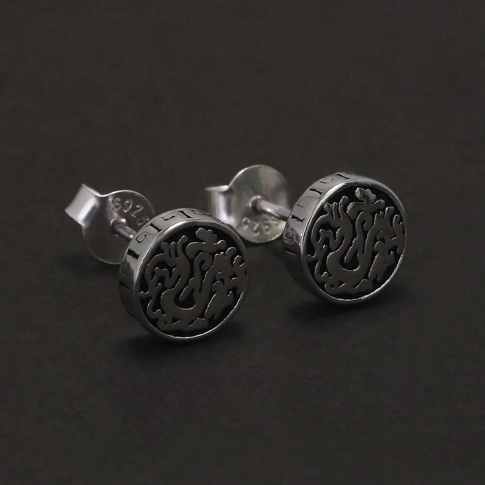 Close-up of Viking dragon stud earrings in oxidized 925 sterling silver on black background