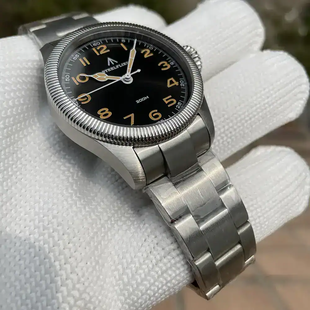 Stainless steel watch featuring a black dial, gold accents, and a durable 20ATM water resistance.