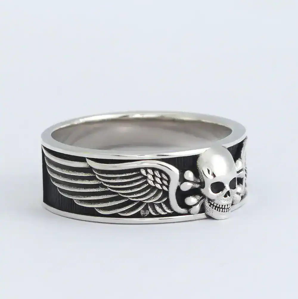 Silver skull and wing motif biker ring, edgy unisex jewelry accessory.