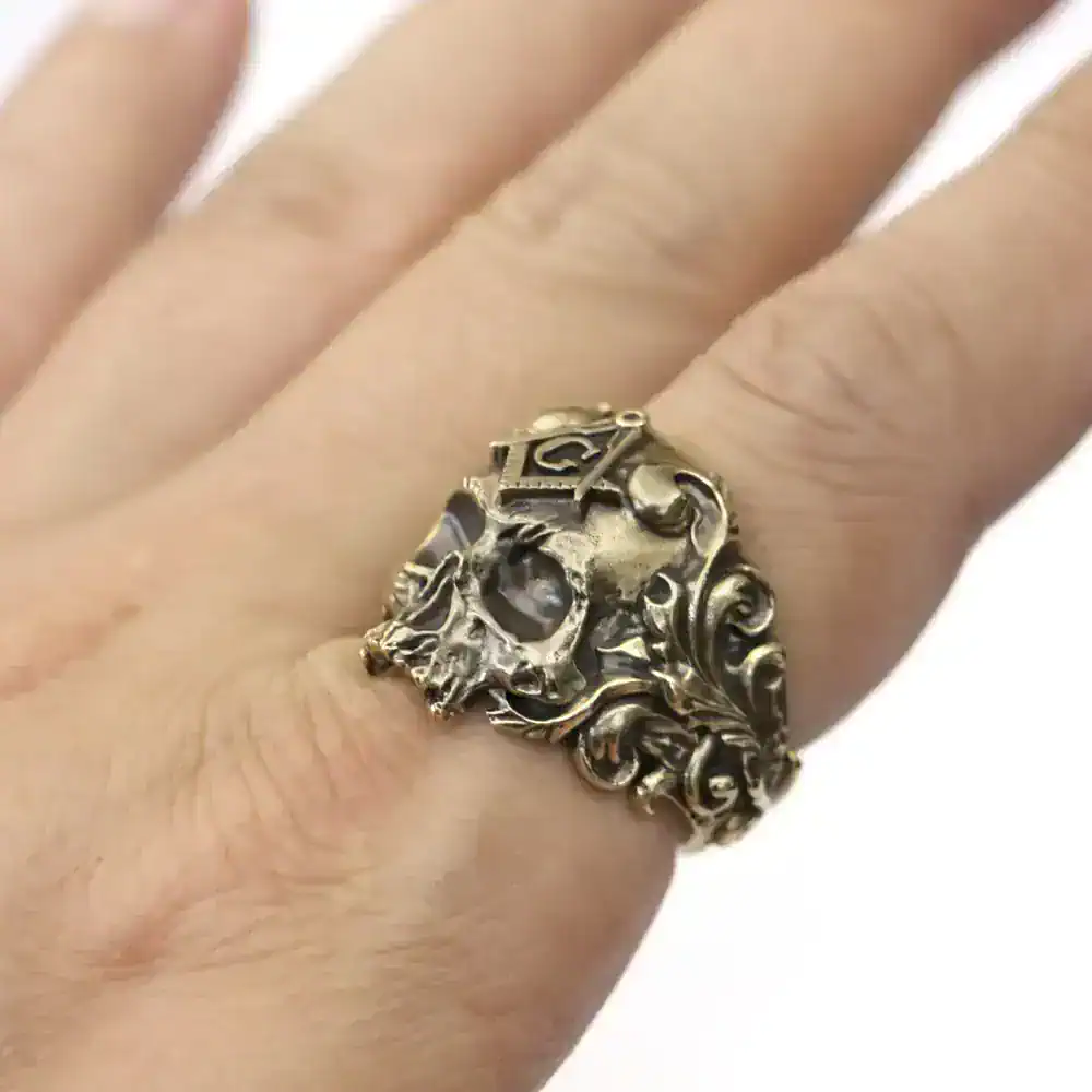 Detailed skull-shaped silver ring with ornate scrollwork design. Perfect for edgy, Gothic style jewelry fans.