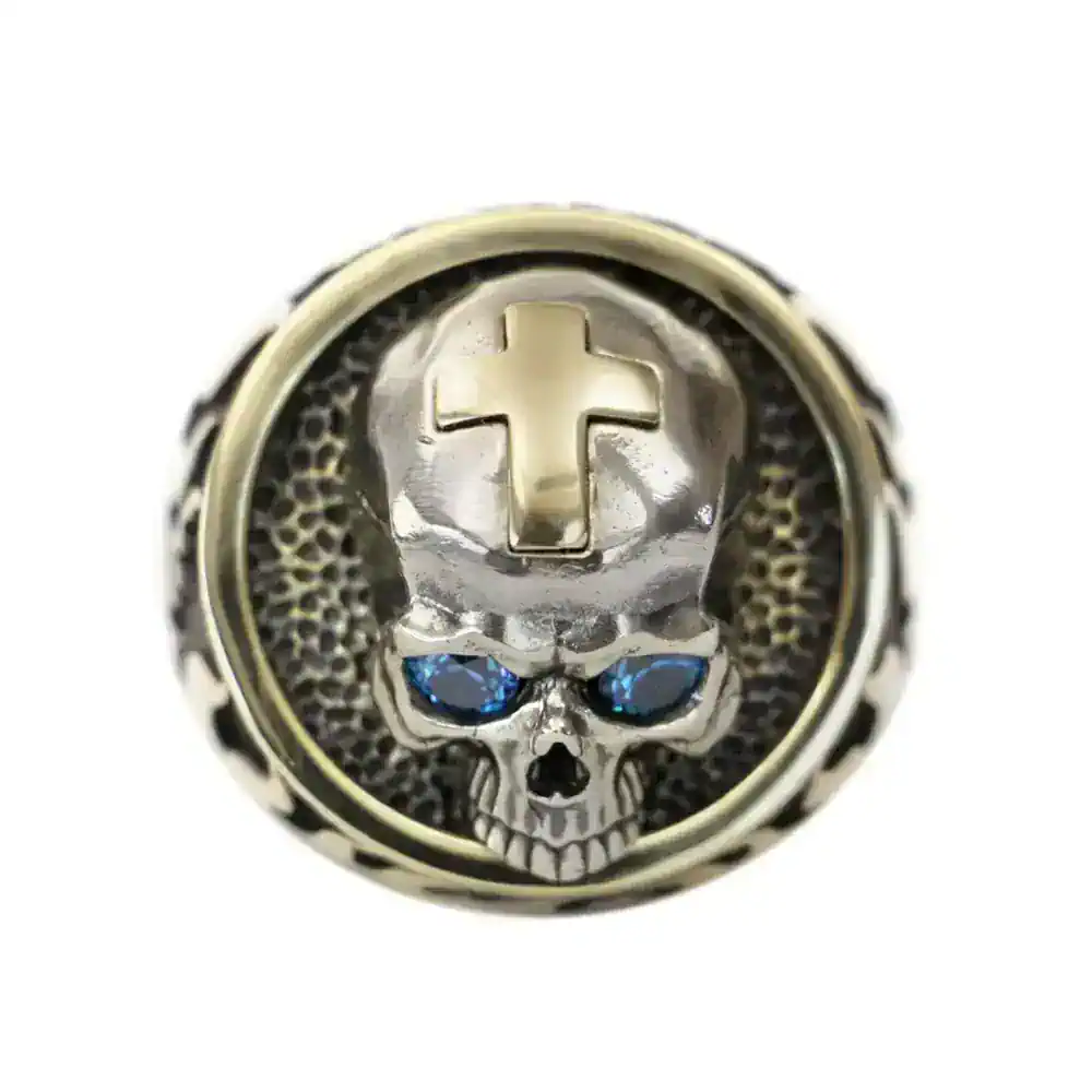 Metal skull pin with blue gemstones and cross detail.