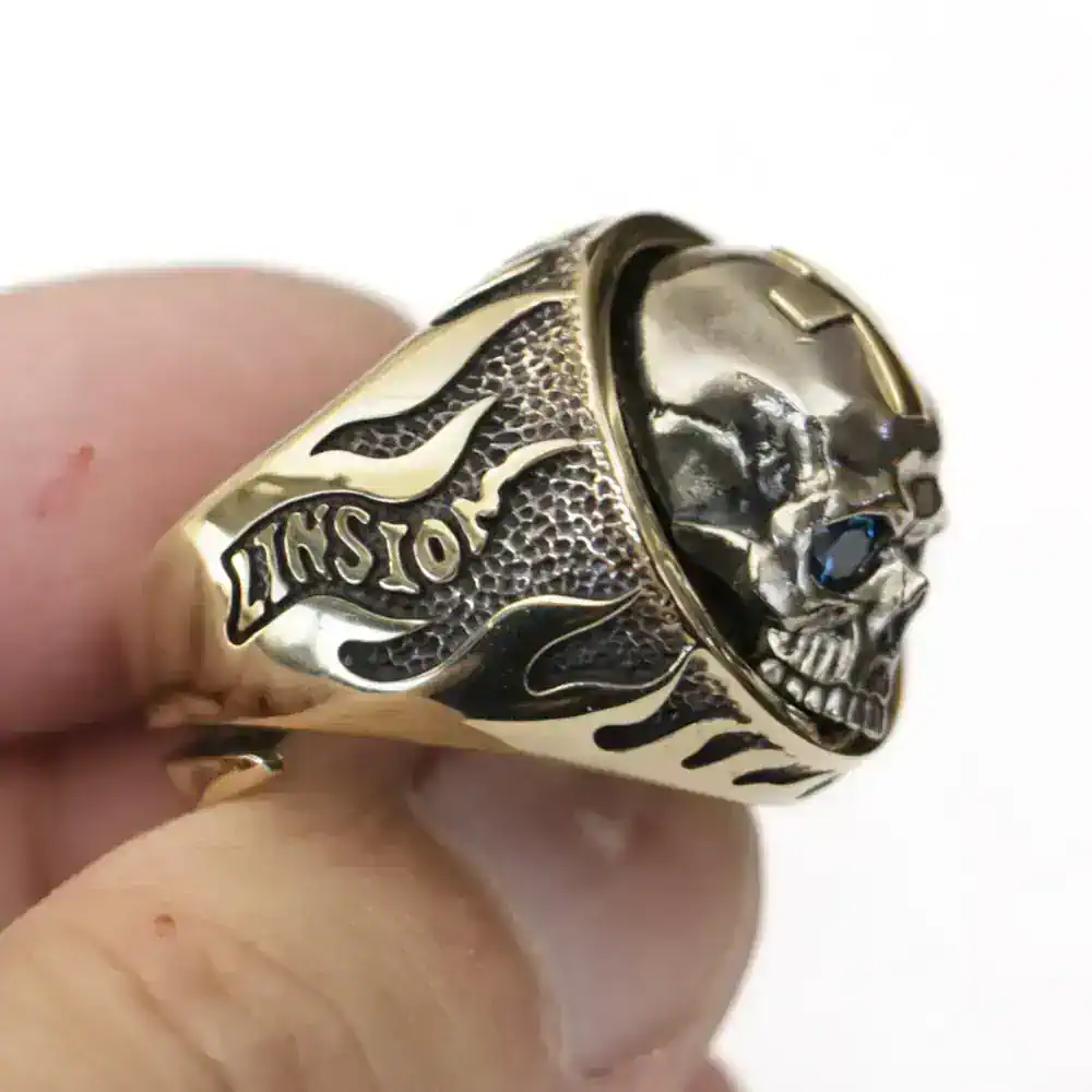 Golden skull ring with black gemstone eye and detailed tattoo design on bands. Perfect for edgy jewelry lovers.