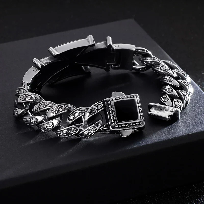Elegant silver chain bracelet with black onyx centerpiece, detailed with floral accents.