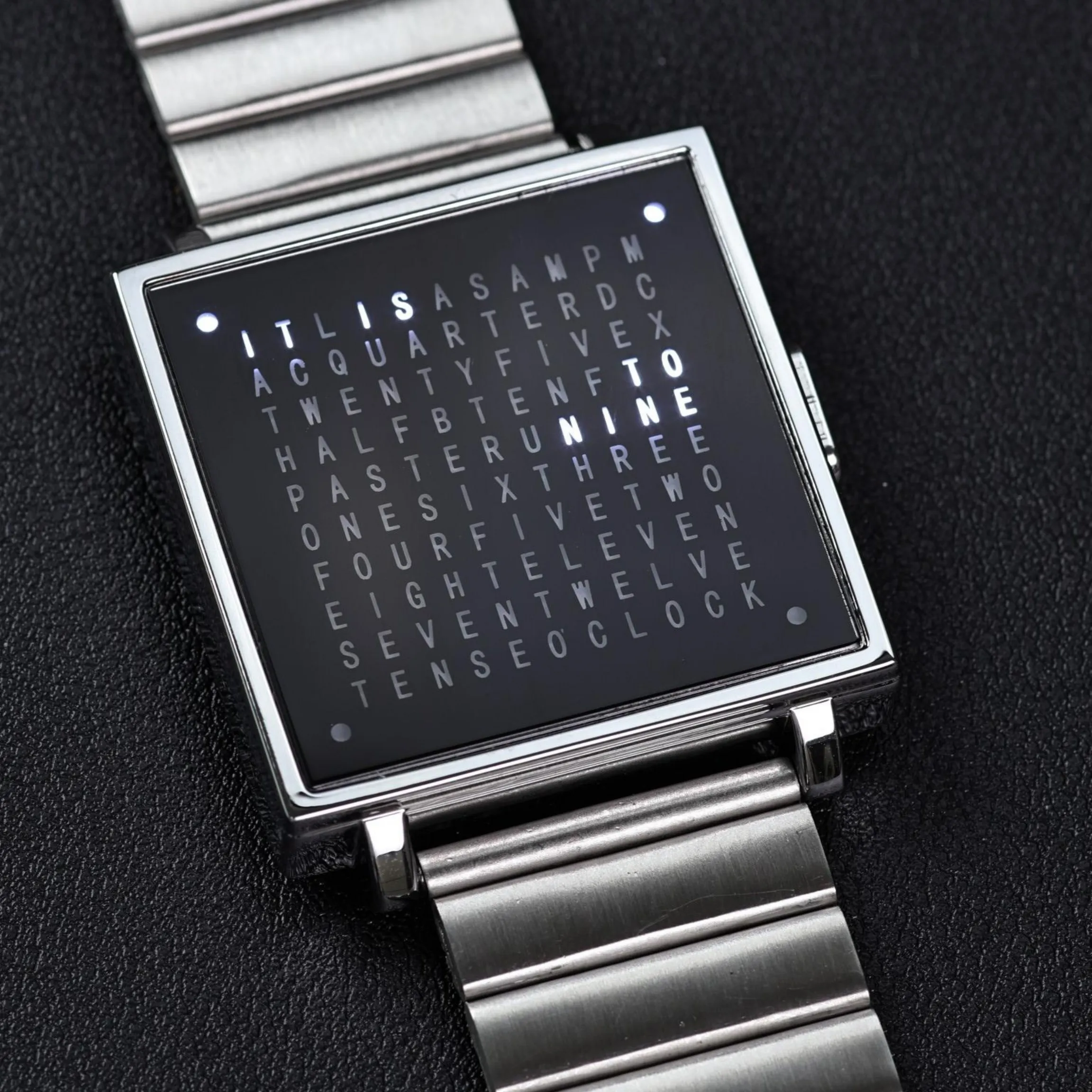 A close-up of a sleek digital smartwatch featuring a word search game on its display, highlighting stylish jewelry and tech accessories.