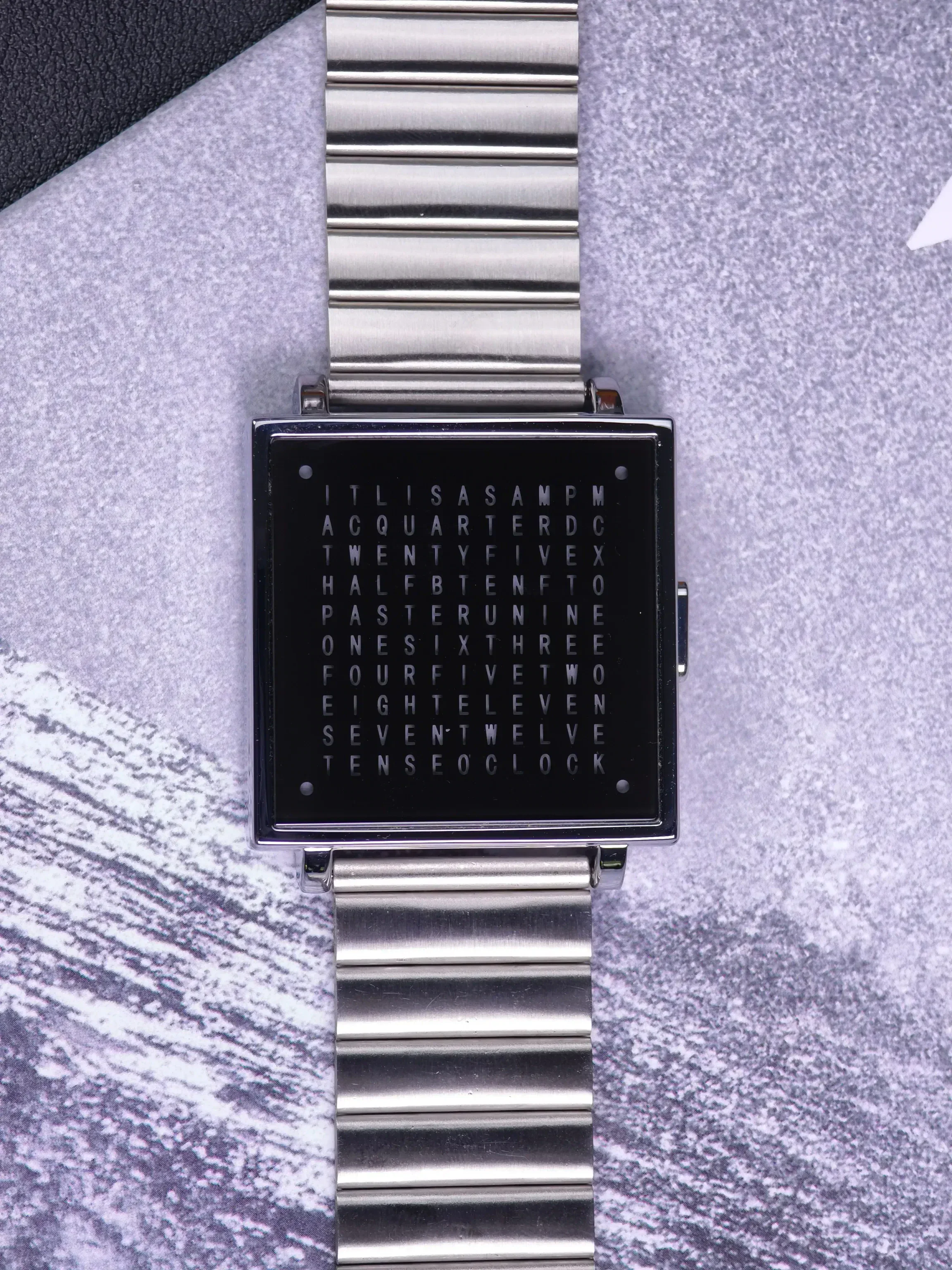 Silver smartwatch with digital word puzzle display for modern style.
