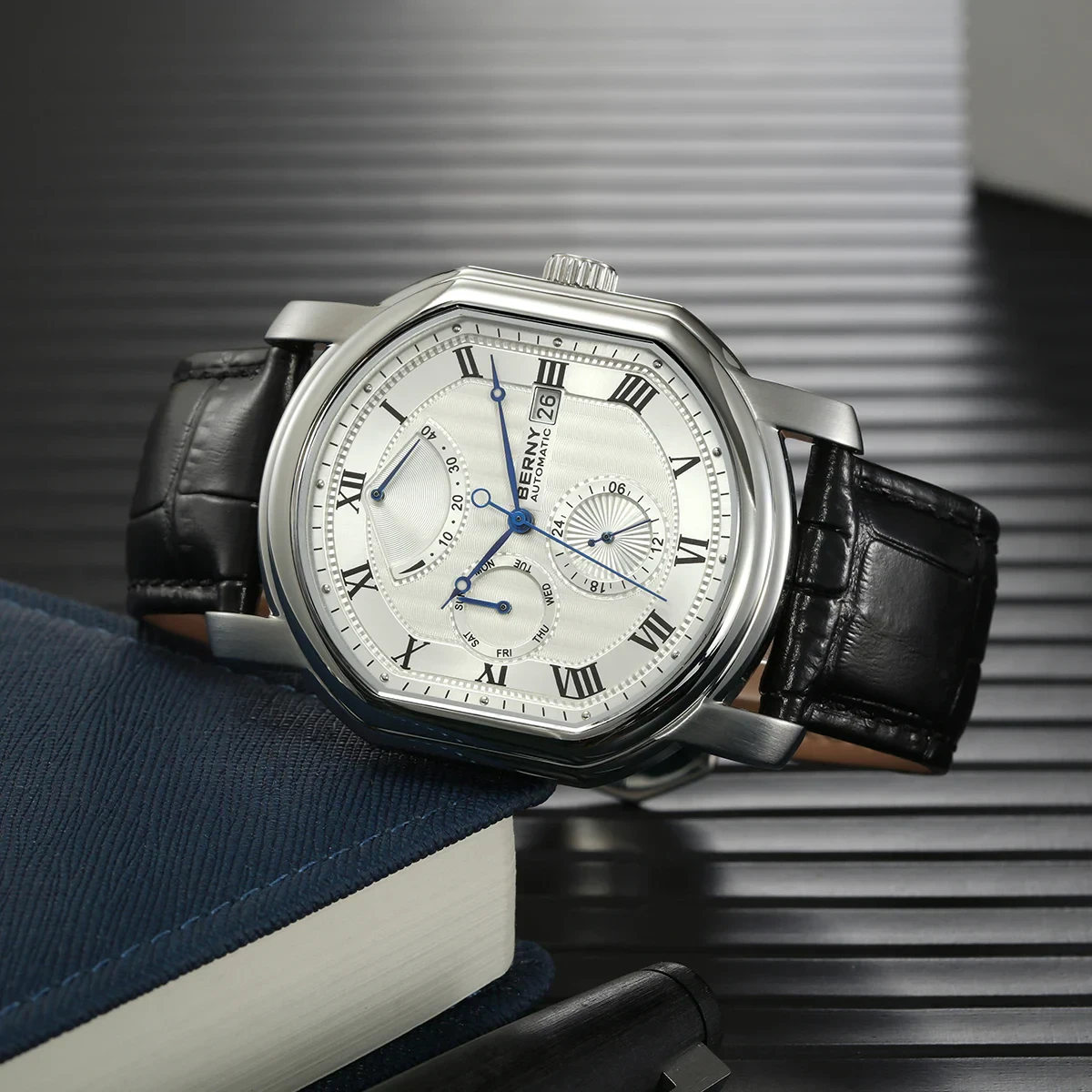 High-end stainless steel watch with black leather band, chronograph features, and Roman numeral dial design.