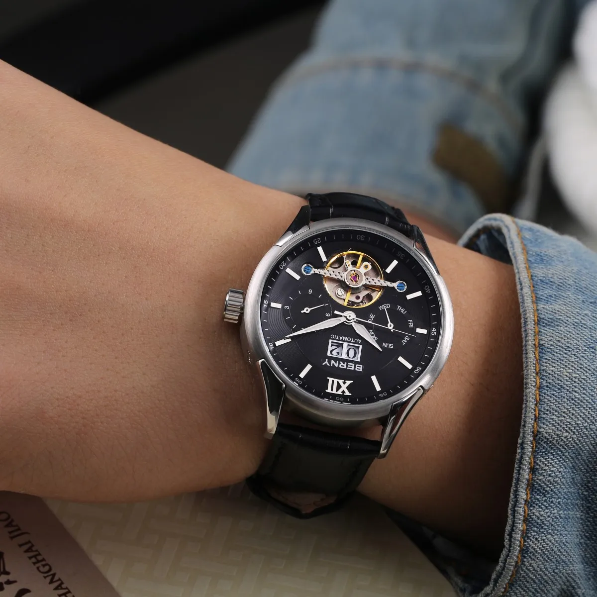 Elegant men's automatic wristwatch with open-heart dial, chronograph, and black leather strap.
