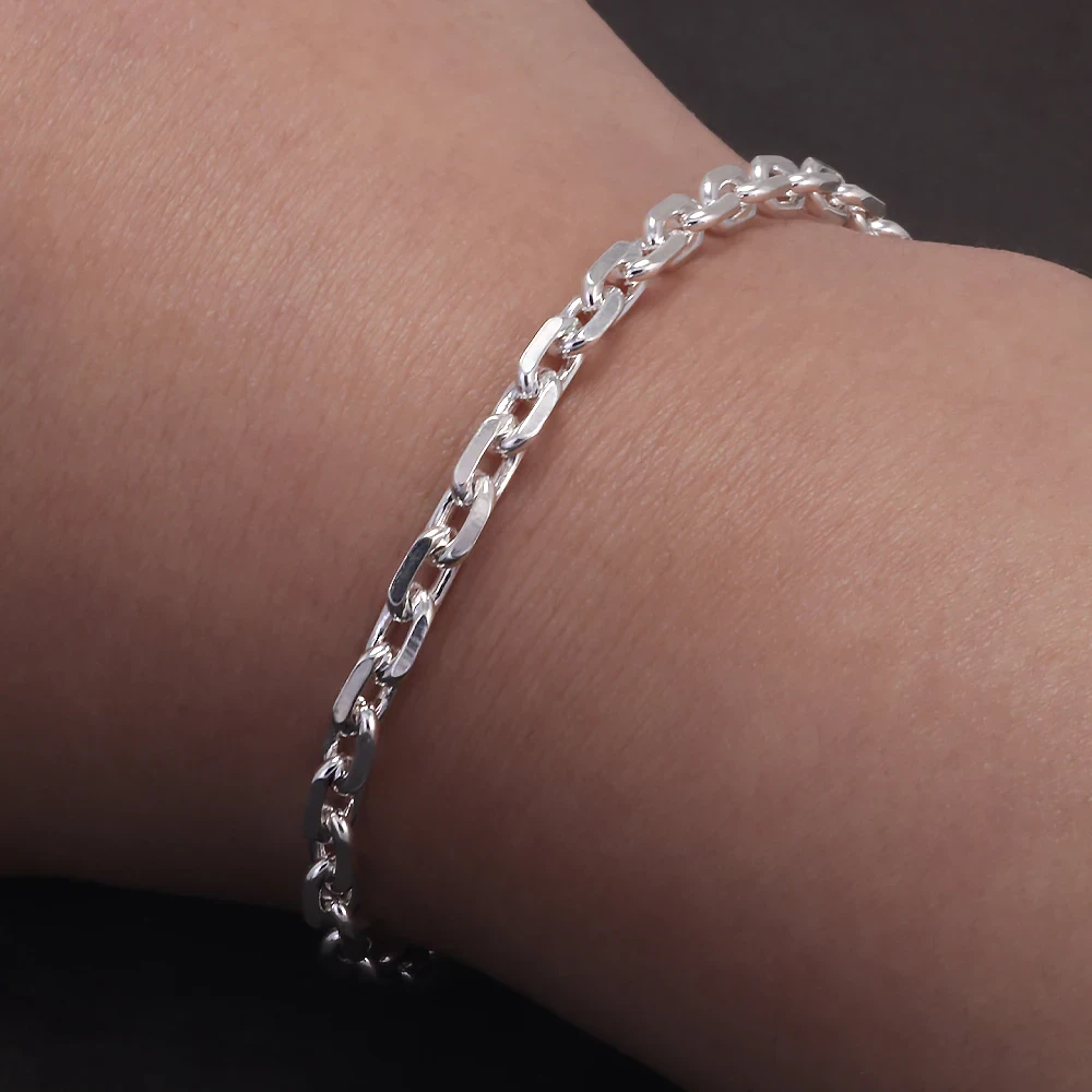 Close-up of silver chain bracelet on wrist, showcasing sleek and stylish jewelry design.