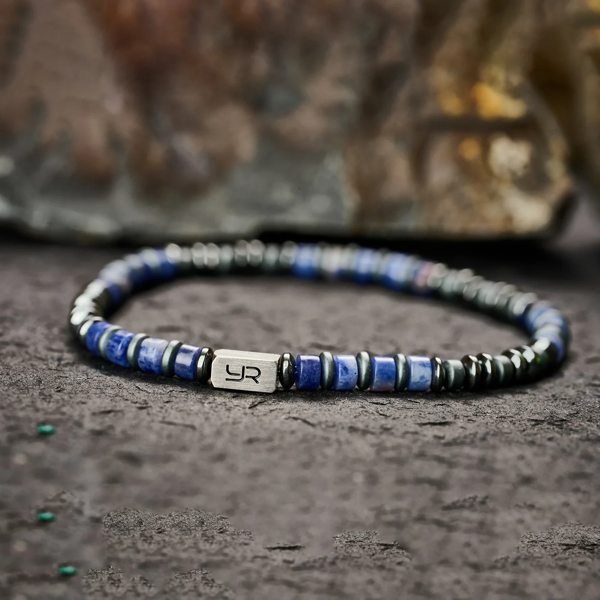 Stylish men's beaded bracelet featuring blue and black beads with a silver UR logo tag.