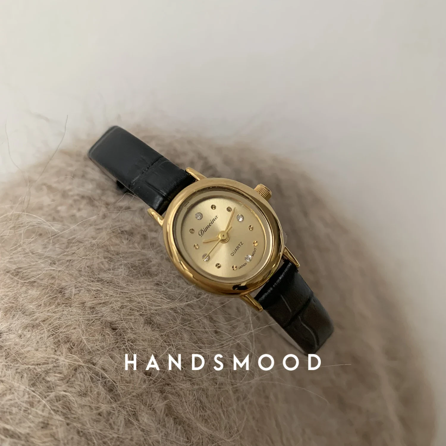 Gold watch with black leather strap, fashionable women’s jewelry piece for everyday wear.