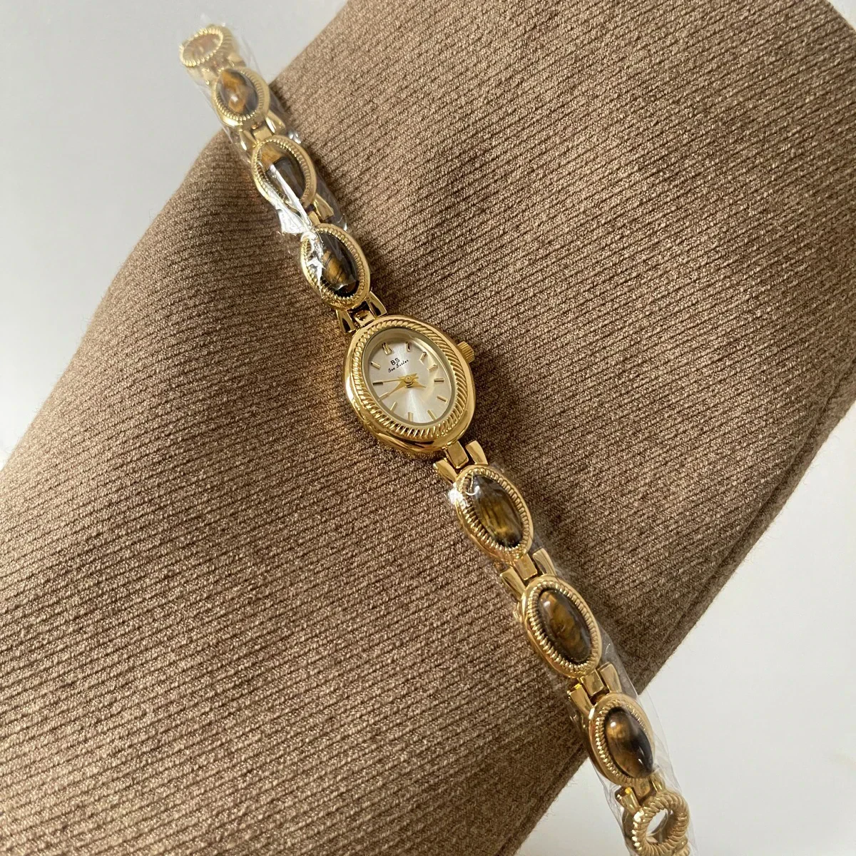 Luxurious gold watch featuring a classic face and oval brown gemstone accents on a sleek bracelet.