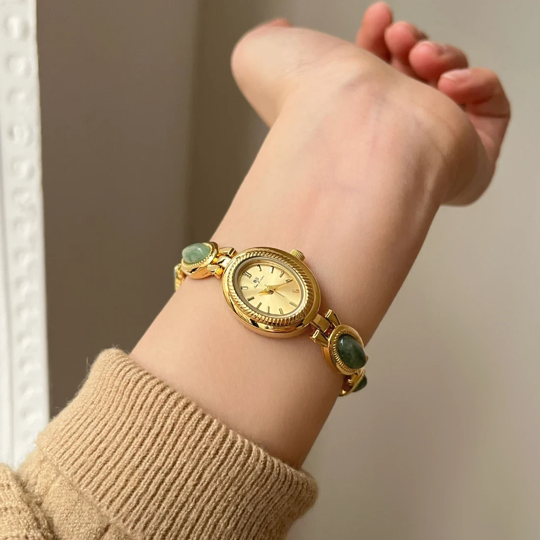 Luxurious gold watch adorned with green gemstone accents for timeless style.