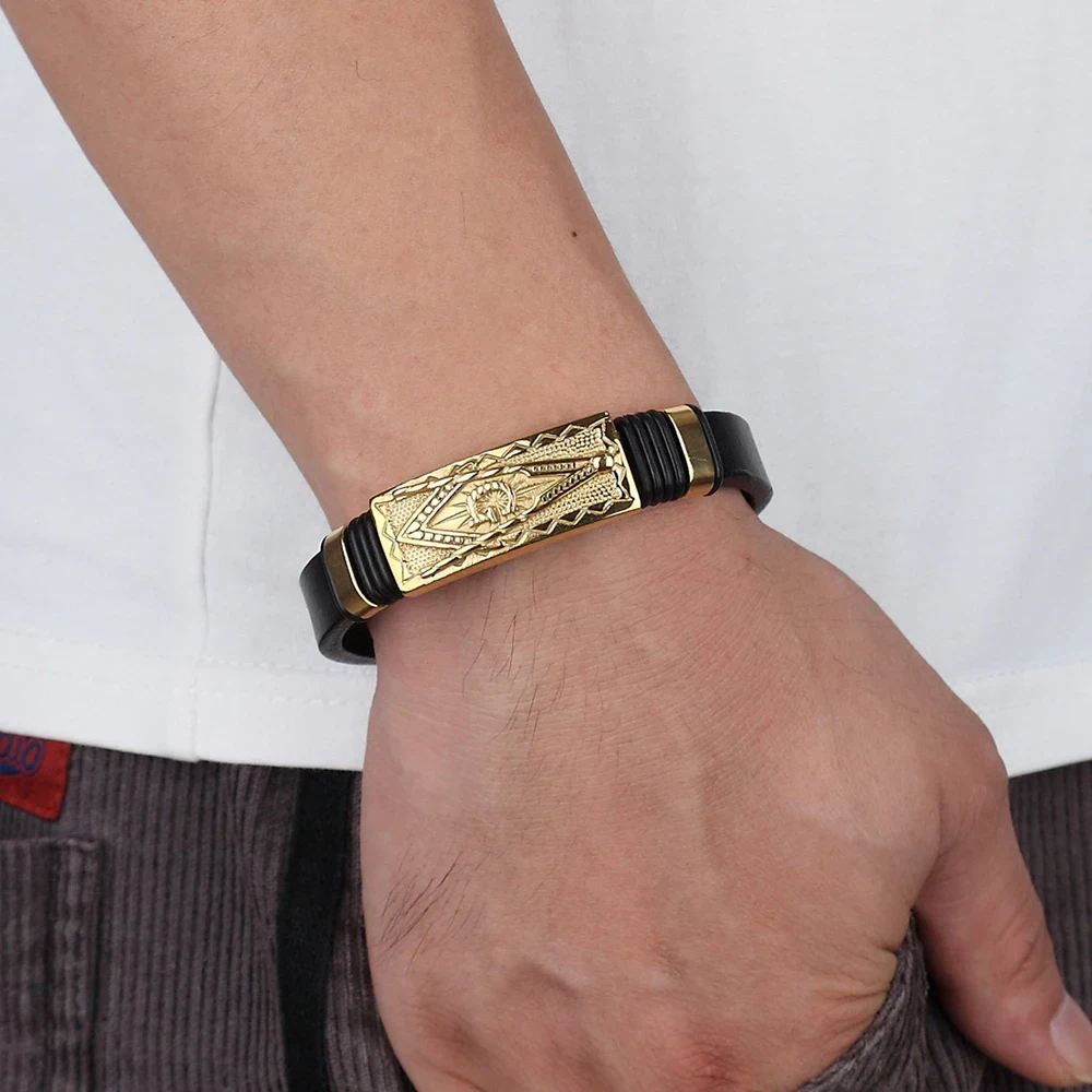 Close-up of men's black leather bracelet with a detailed gold-tone tribal-inspired centerpiece.