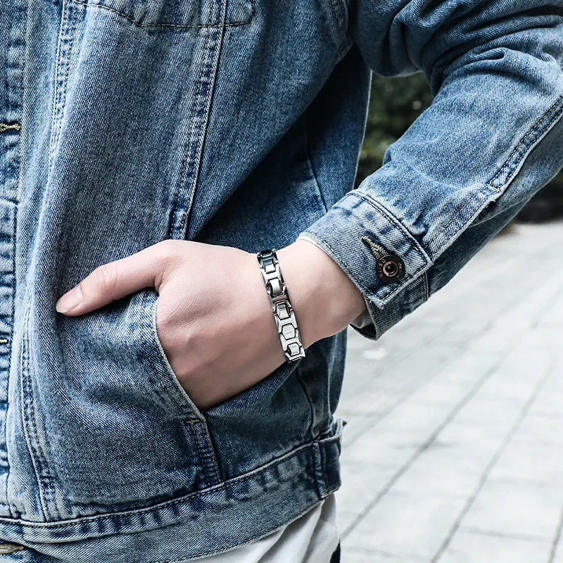 Modern silver bracelet on man's wrist with denim jacket backdrop.