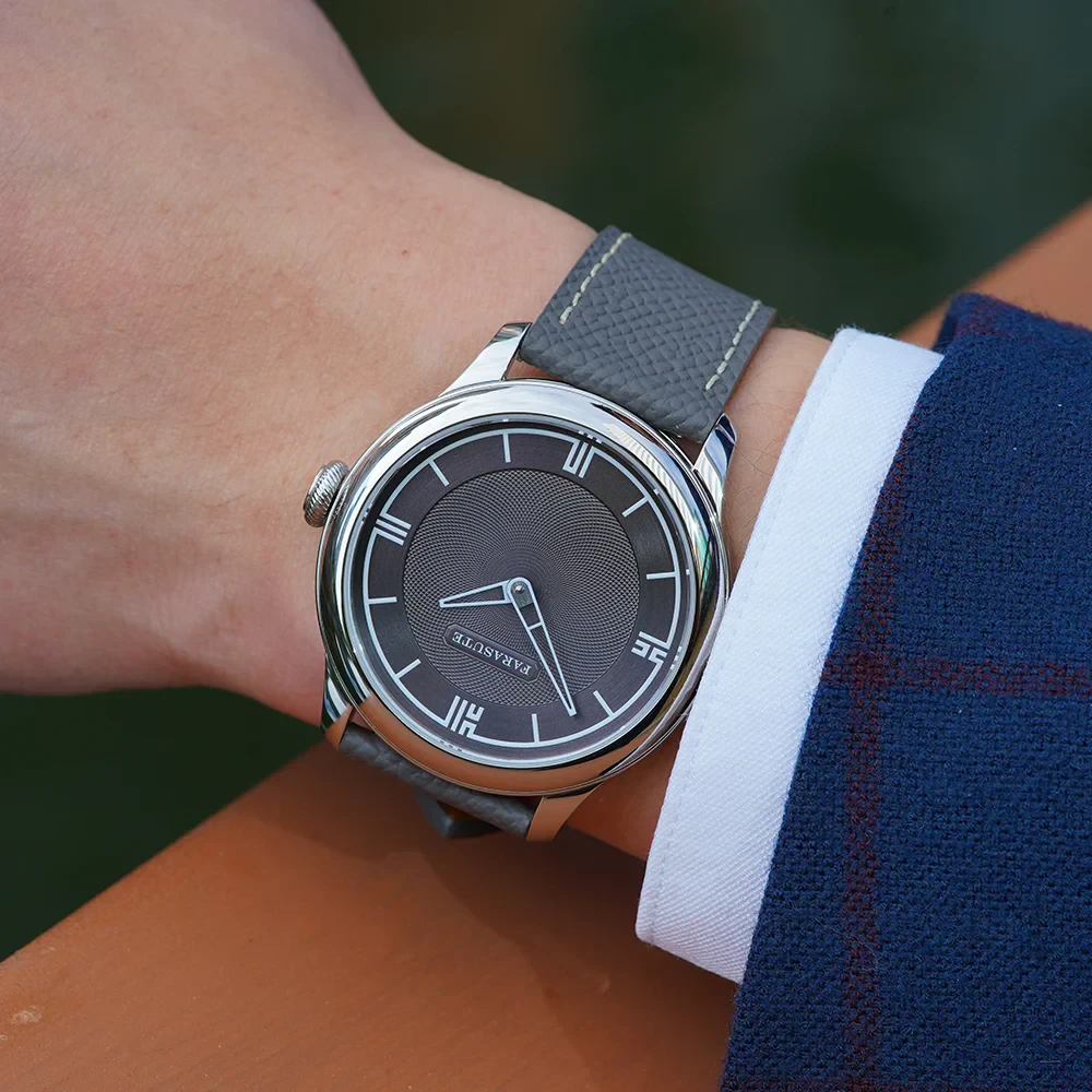 A stylish men's wristwatch featuring a black dial, silver case, and gray leather strap, ideal for sophisticated jewelry collections.