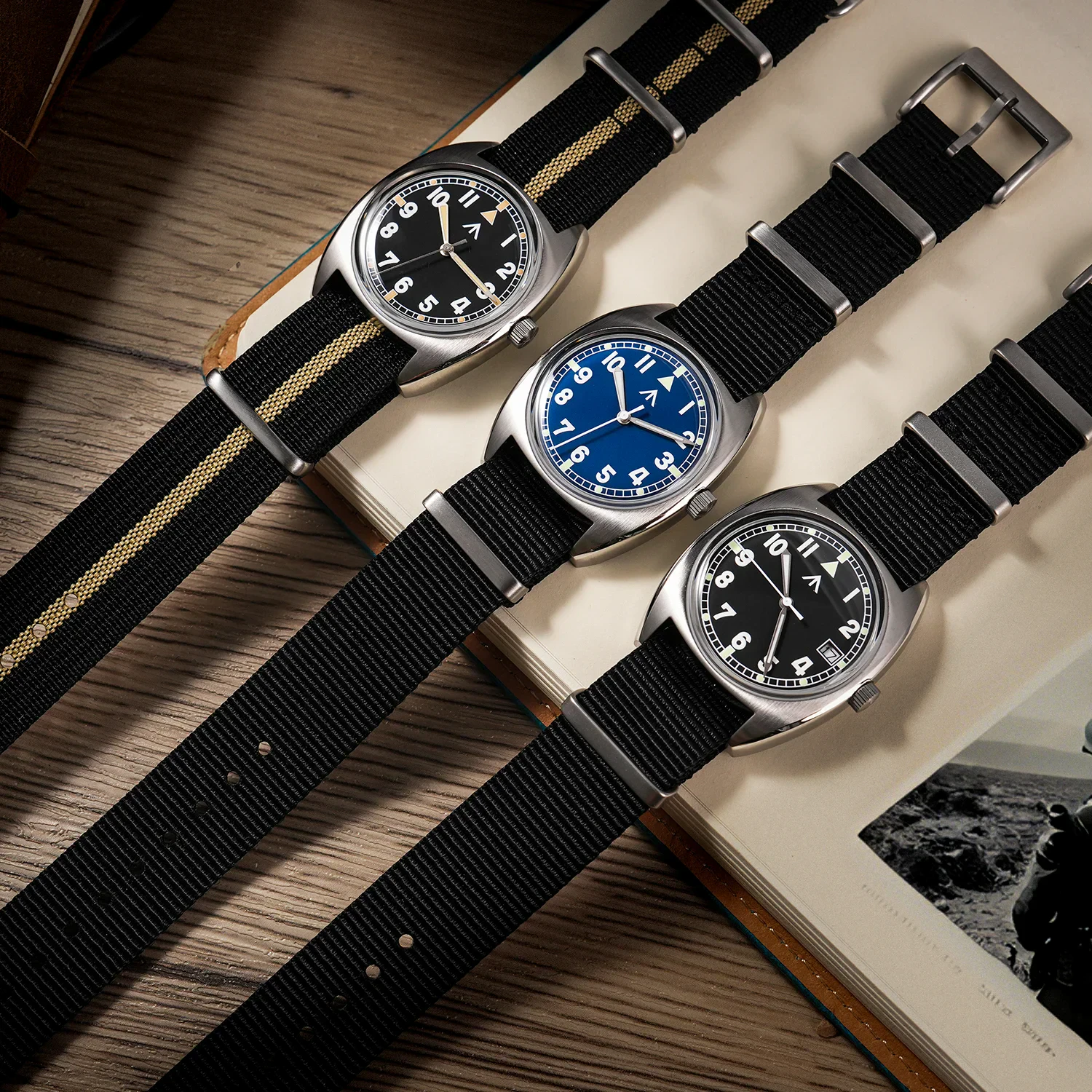 Three military-style wristwatches with nylon straps in black, blue, and black with white accents.