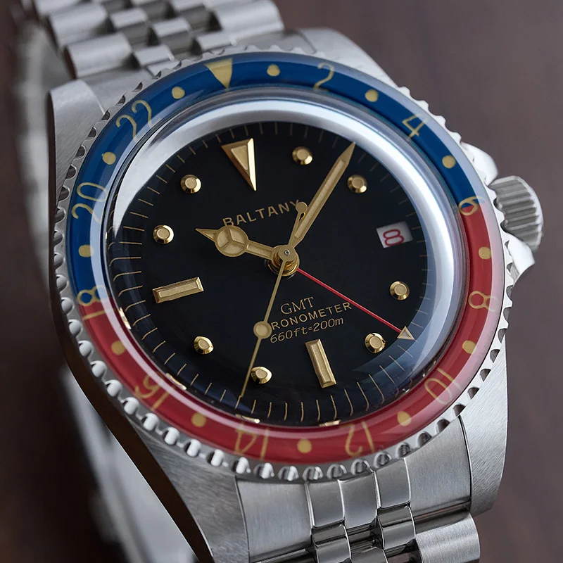 Baltic GMT dive watch with black dial, gold accents, and stainless steel bracelet.