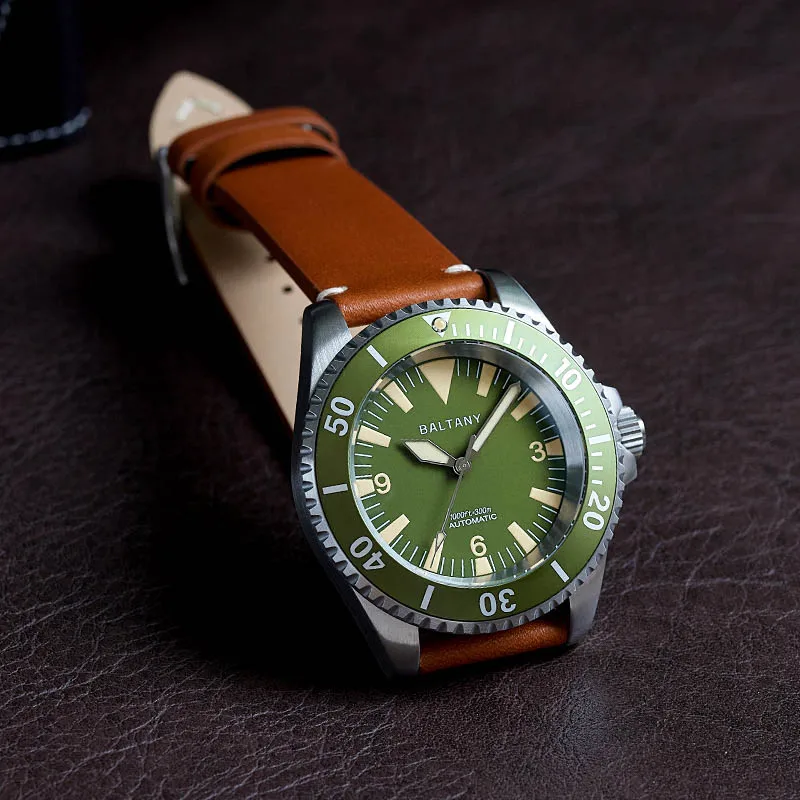 Green dial dive watch with stainless steel case and brown leather strap.