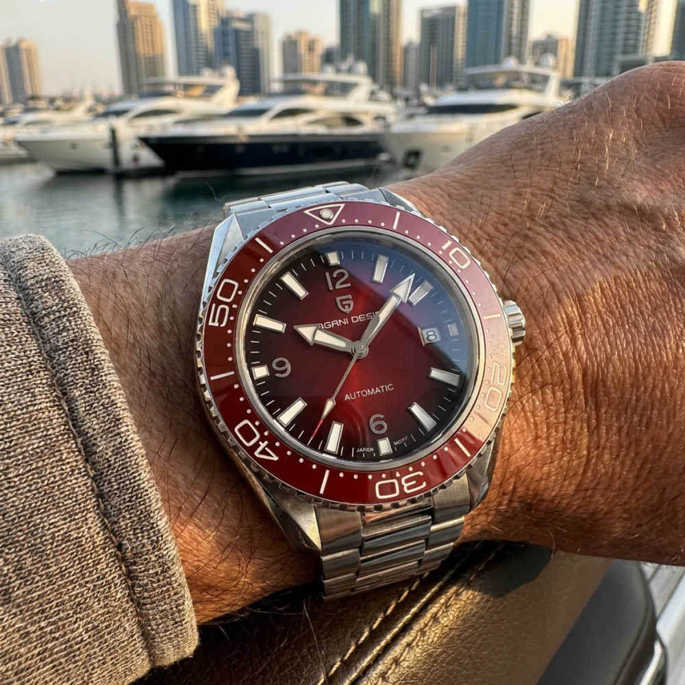 Red and silver automatic dive watch on a man's wrist with a marina background.