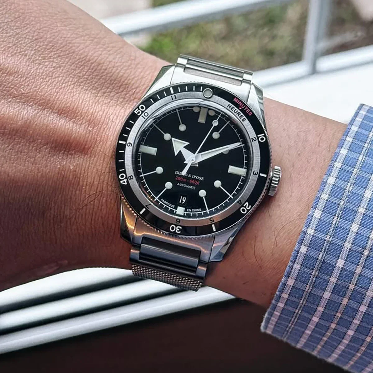 Men's luxury diver watch featuring a black dial, luminous hands, and a stainless steel mesh strap. P.