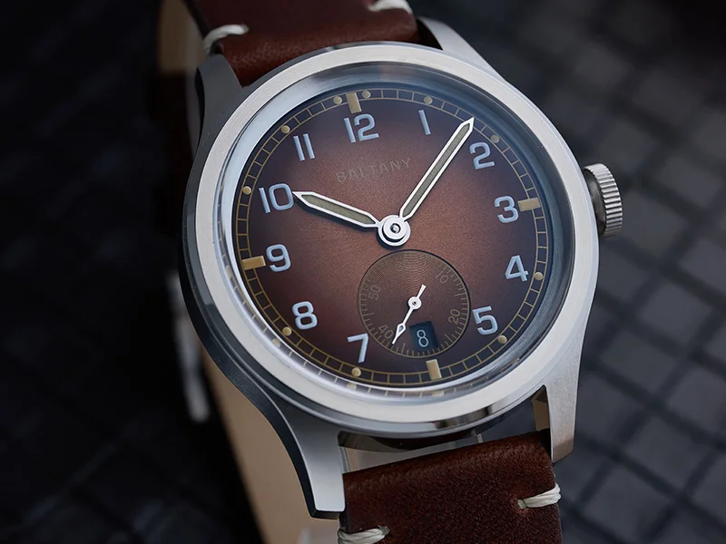 Brown dial wristwatch with silver case and leather strap.